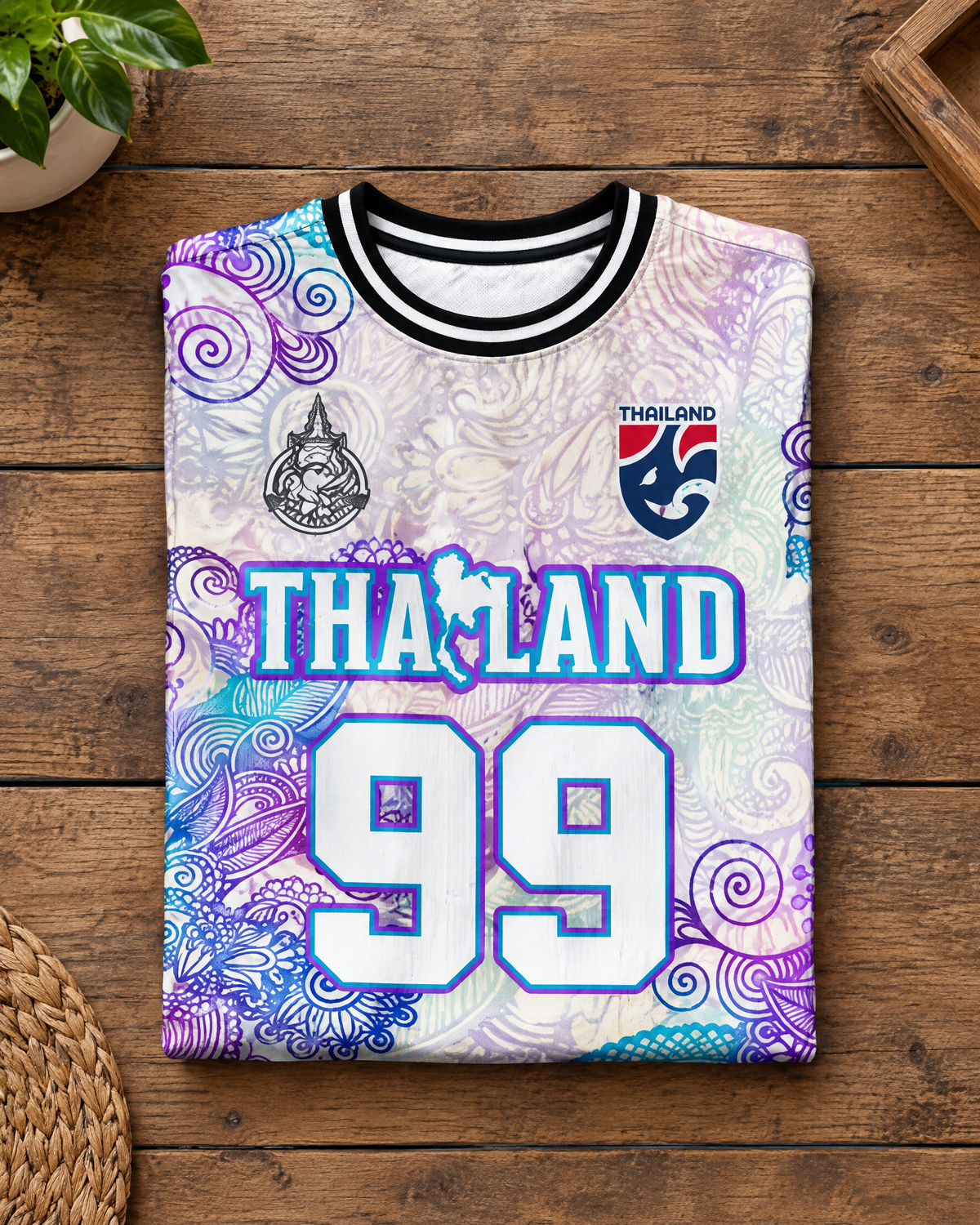 Illustratives Produkt-Mockup: Thailand Trikot Nr. 99 Lila Mandala gefaltet auf Holztisch